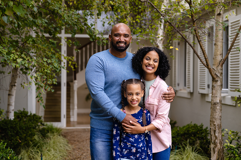 portrait-of-happy-biracial-parents-and-daughter-em-2025-04-03-10-38-23-utc copy Family posed together in front of their home